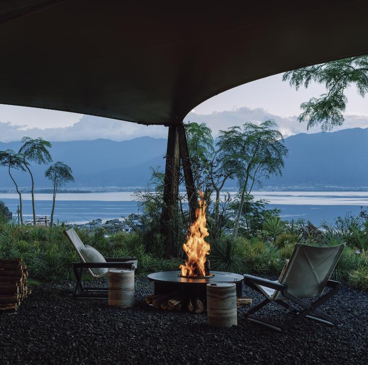 An outdoor fire pit and lounge terrace with the mountains beyond.