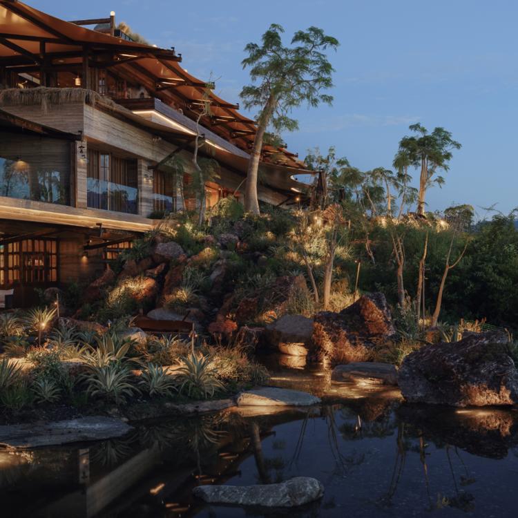 The hotel facade at dusk, garden and reflecting pond in front.