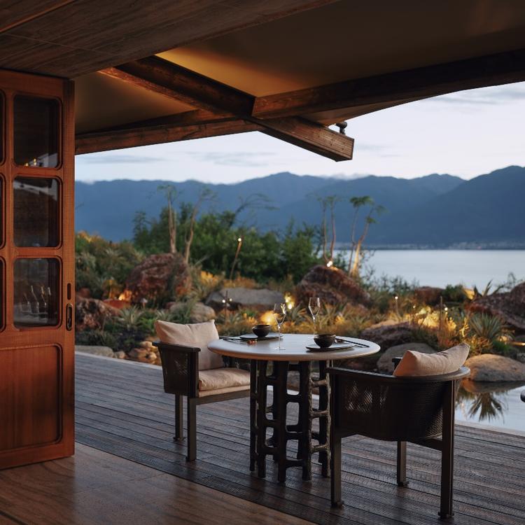An outdoor table set for dinner above the lake.